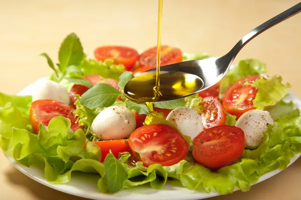 Olio d'oliva versato sull'insalata — Foto Stock