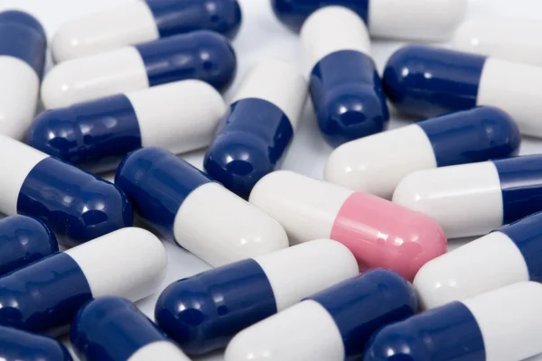 Modré a růžové tobolka pilulek na bílém pozadí — Stock fotografie