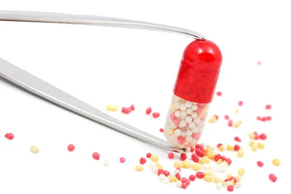 Red capsule pill in a tweezers isolated — Stock Photo, Image