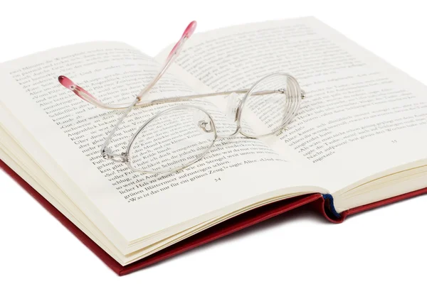 Öppna bok med glasögon på det — Stockfoto