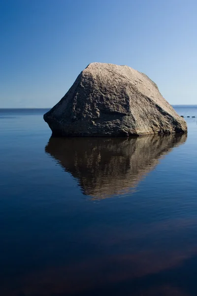 Самотній камінь у блакитній воді — стокове фото