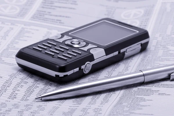 Jornal com caneta e telefone celular — Fotografia de Stock
