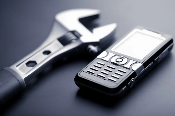 Mobiele telefoon en moersleutel — Stockfoto