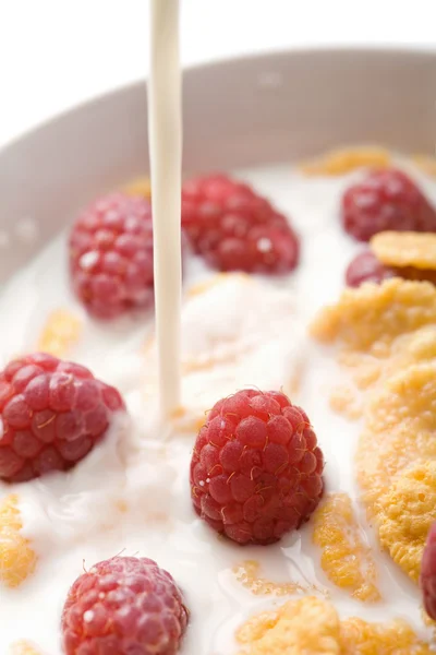 Milk pouring onto muesli with raspberry — Stock Photo, Image