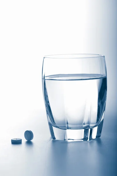 Pastillas de aspirina y vaso de agua — Foto de Stock