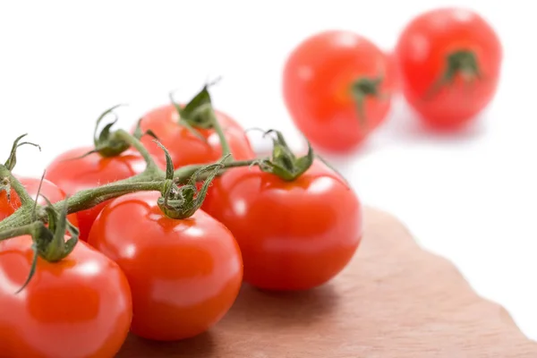 Tomates maduros sobre tábua de madeira isolada — Fotografia de Stock