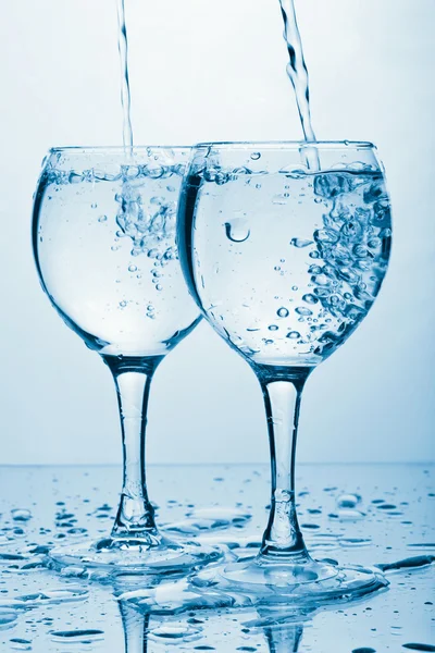 Pure water splashing into two glasses — Stock Photo, Image