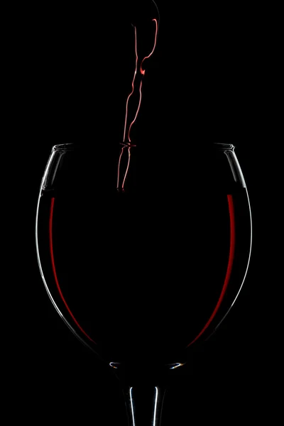 Red wine pouring into glass silhouette — Stock Photo, Image