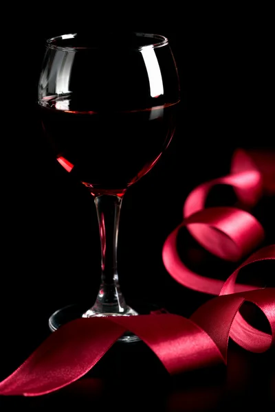 Glass of red wine and red ribbon — Stock Photo, Image