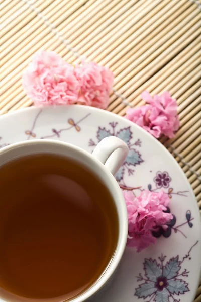 Kopje thee en bloemen over bamboe mat — Stockfoto