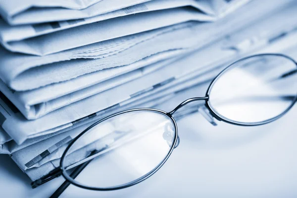 Zeitungen und Brillen blau getönt — Stockfoto