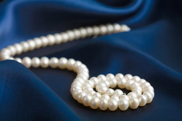 Pearl necklace over blue silk — Stock Photo, Image