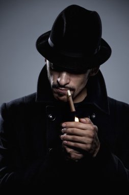 Mysterious man lighting a cigarette clipart