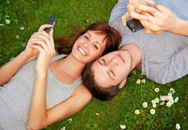 Young couple with mobile phones outdoors clipart