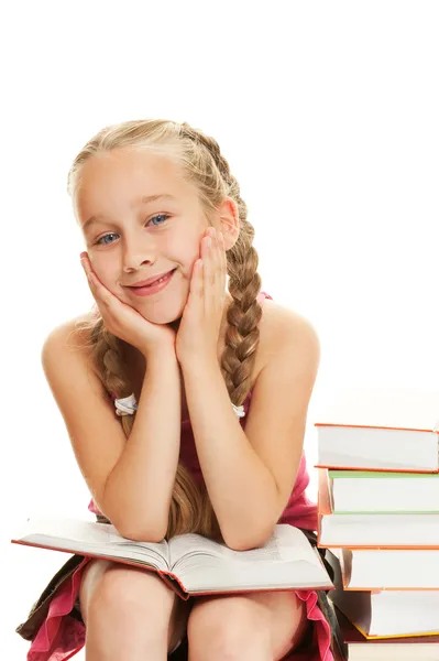 Happy little schoolgirl sitting on books — Stock Photo, Image