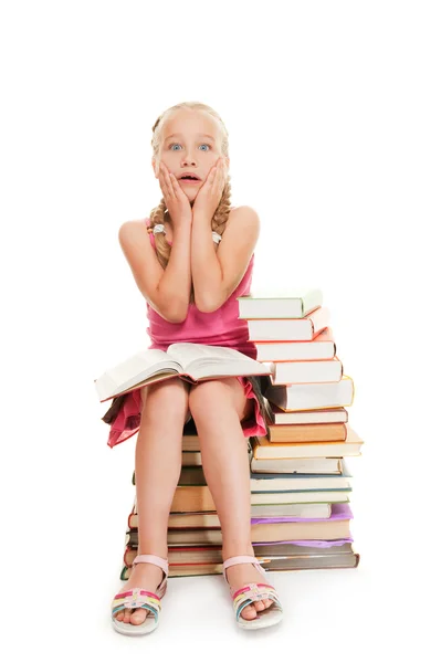 Liten skolflicka sitter på böcker — Stockfoto