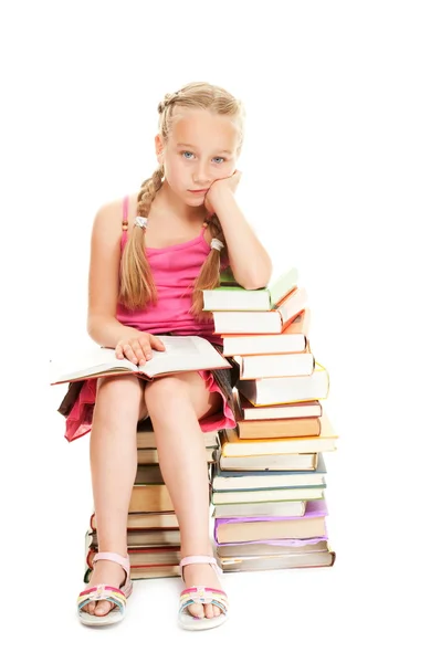 Kleines Schulmädchen sitzt auf Büchern — Stockfoto