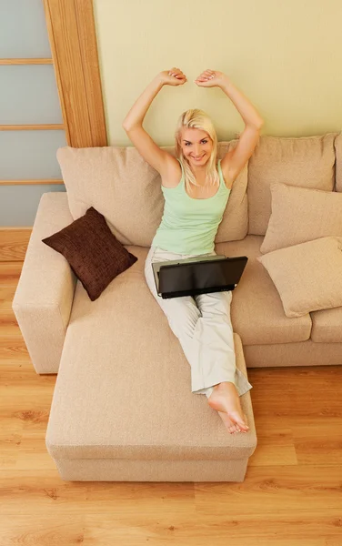 Mujer joven sentada en un sofá con portátil — Foto de Stock
