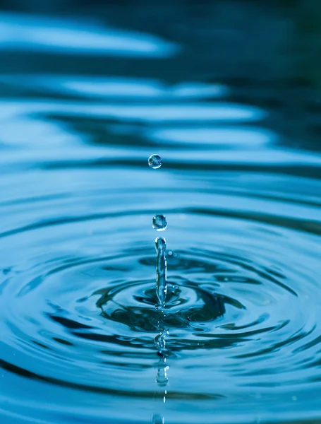Kapky padající v modré vodě — Stock fotografie