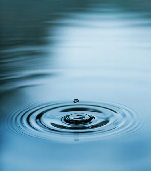 Gotas caindo na água azul — Fotografia de Stock