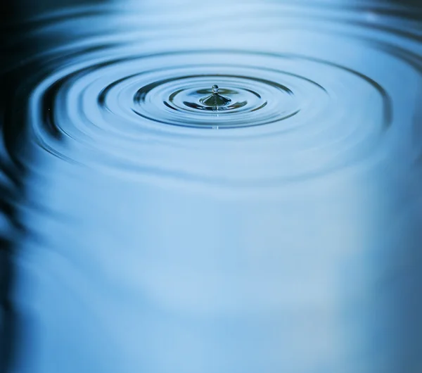 Droplet falling in blue water — Stock Photo, Image