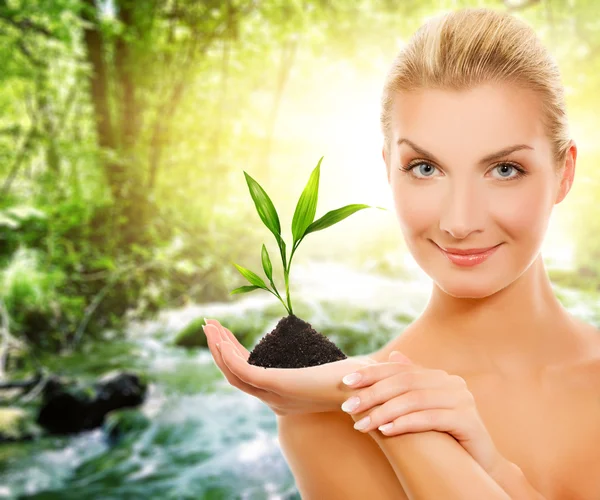 Woman with young plant in forest — Stock Photo, Image