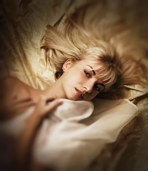 Schönes blondes Mädchen, das in einem Bett liegt — Stockfoto