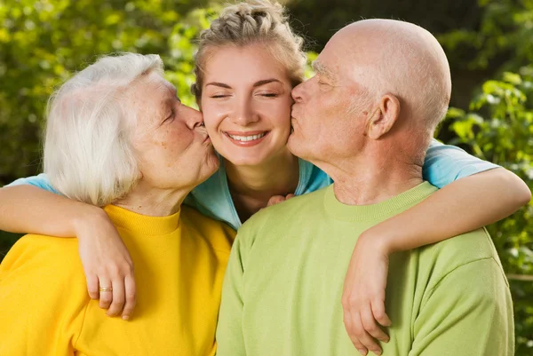 Бабушка и дедушка целуют внучку — стоковое фото