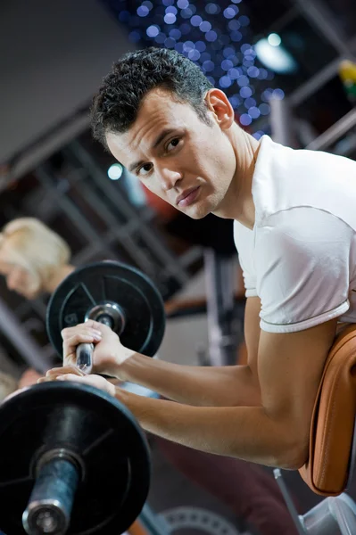 Handsome man lifting weight in a gym — Stock Photo, Image