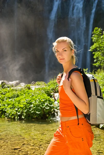 Turysta z plecaka w pobliżu wodospadu — Zdjęcie stockowe