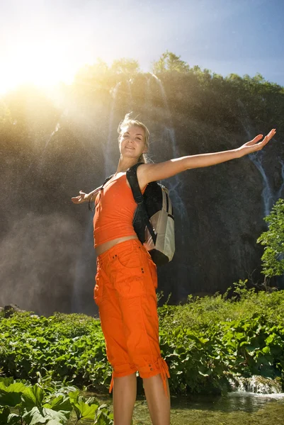 Glad turist nära vattenfall i en skog — Stockfoto