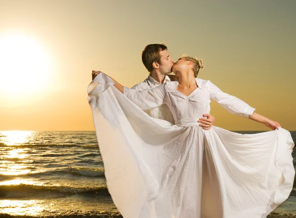 Par i kärlek på en strand i solnedgången — Stockfoto