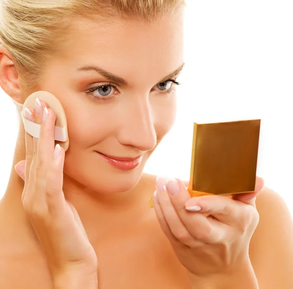 Mujer joven que se aplica maquillaje en la cara — Foto de Stock