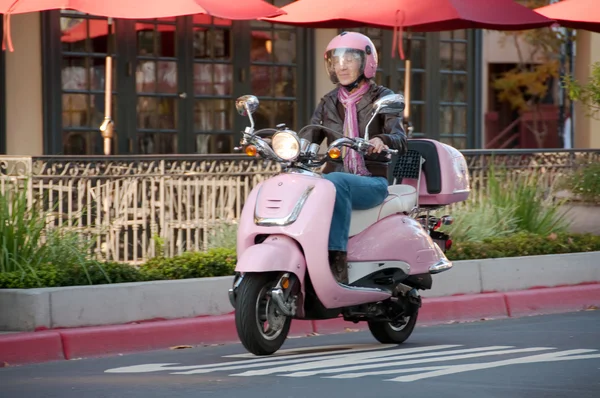 Lady biker zipping along on her pink sco Stock Picture
