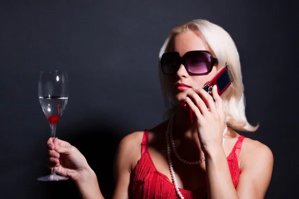 Blond kvinna med telefon och glas — Stockfoto