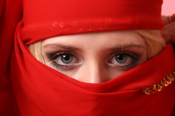 Mooi meisje achter een rode sjaal — Stockfoto