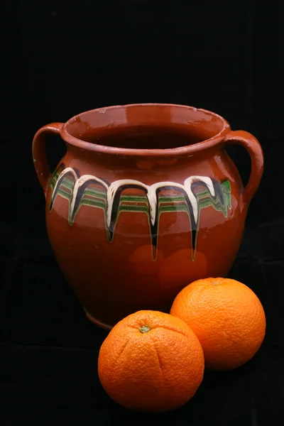 Panela de cerâmica e laranjas — Fotografia de Stock