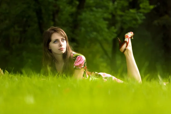 Jovem menina bonita em uma grama — Fotografia de Stock