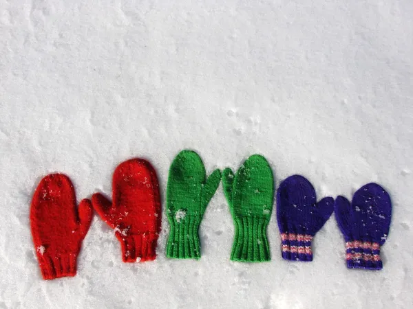Three pairs mittens in the snow — Stock Photo, Image
