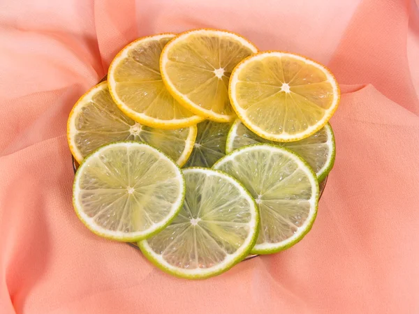 Limão e limão sobre um fundo rosa — Fotografia de Stock