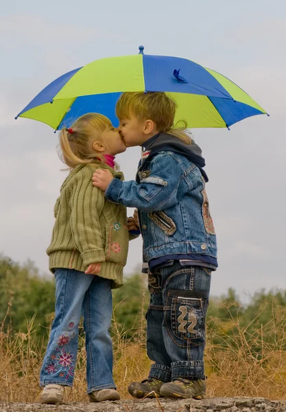 Мальчик и девочка с зонтиком — стоковое фото