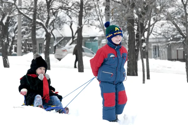 Brother pulling sister on sledge — Stock Photo, Image