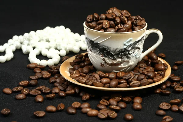 Coffee beans in a cup and beads — Stock Photo, Image