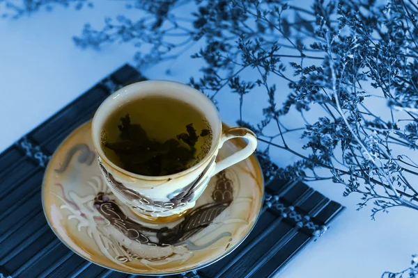 Chá verde em uma xícara com folhas de chá — Fotografia de Stock