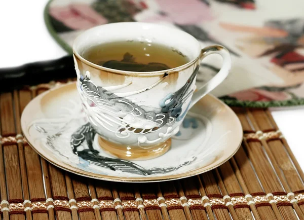 Cup of green tea and a fan isolated — Stock Photo, Image