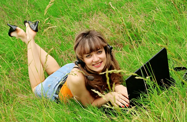 잔디에 노트북으로 젊은 여자를 웃 고 — 스톡 사진