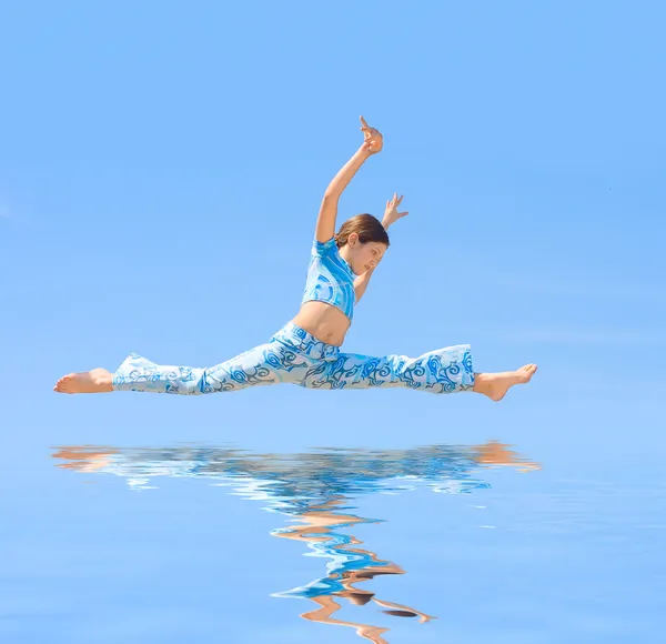 Девочка-подросток прыгает на синем фоне — стоковое фото