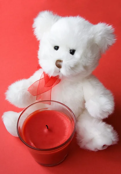Белый плюшевый мишка и красная свеча — стоковое фото