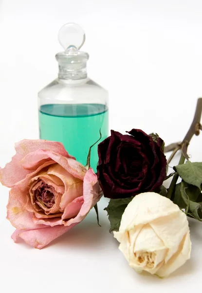 Τρία ξηρά τριαντάφυλλα και μπουκάλι λάδι — Φωτογραφία Αρχείου