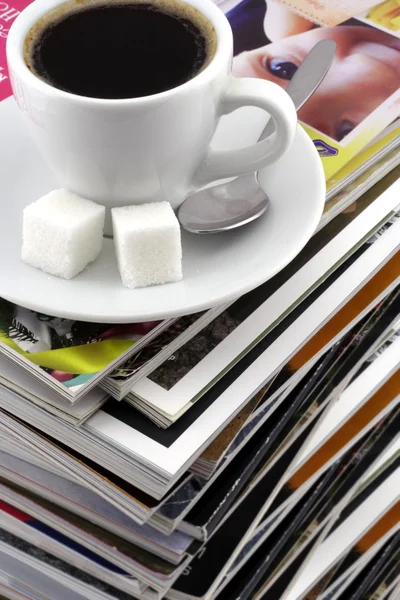 Cup of coffee on a pile of magazines. — Stock Photo, Image